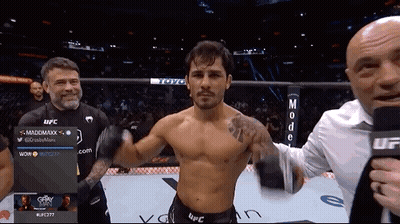 Man In Top Hat Riding Motorcycle Past Football Players GIF