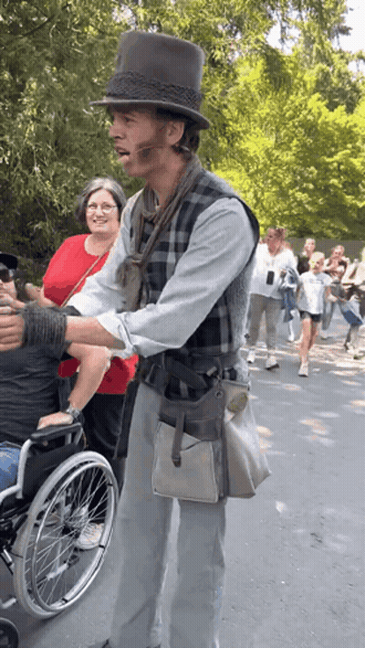 Man In Top Hat Standing Next To Man In Wheelchair GIF