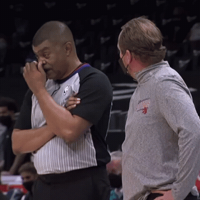 Man In Toronto Raptors Shirt Wiping Nose Talking To Another Man GIF
