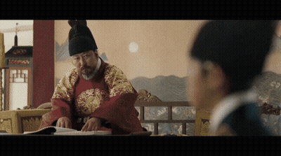 Man In Traditional Costume Reading Book, Another Looking On GIF