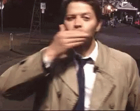 Man In Trench Coat And Tie Covering Mouth GIF