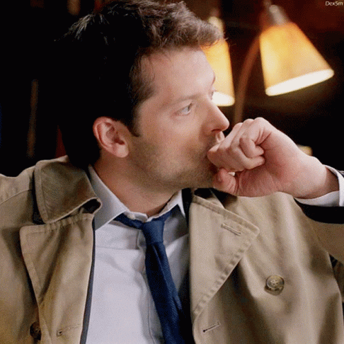 Man In Trench Coat And Tie Holding Hand To Face GIF
