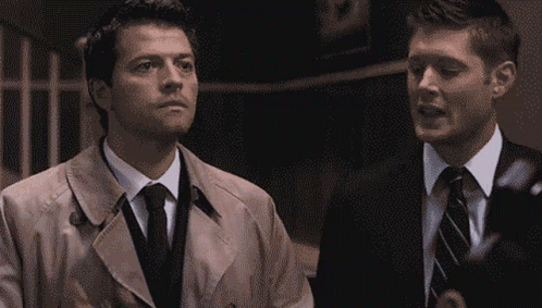 Man In Trench Coat And Tie Next To Man In Suit GIF