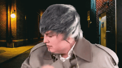 Man In Trench Coat By Brick Building Saying Exit GIF