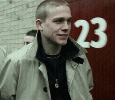 Man In Trench Coat In Front Of Red Wall Number 23 GIF