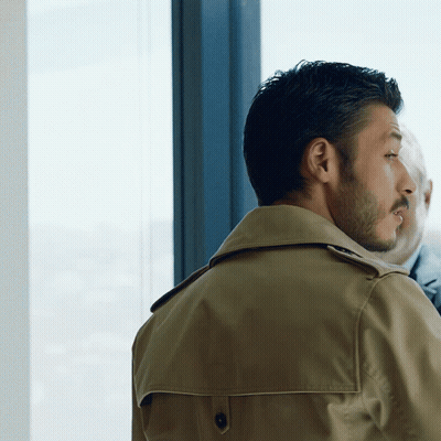 Man In Trench Coat Looking Out Window GIF