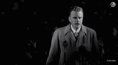 Man In Trench Coat Speaking Into Microphone GIF