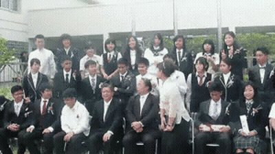 Man In Trench Coat Standing In Crowd GIF