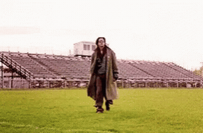 Man In Trench Coat Walking On Soccer Field GIF