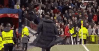 Man In Trench Coat Walking On Soccer Field Surrounded By Security Guards GIF