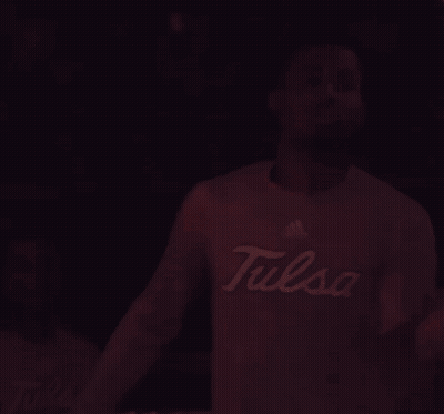 Man In Tulsa Shirt Standing In Dark Room GIF