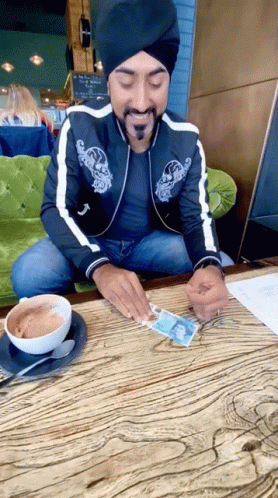 Man in Turban Sitting at Table With Coffee and Paper