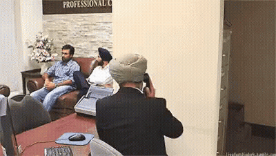 Man In Turban Taking Picture Of Group In Front Of Professional Sign GIF