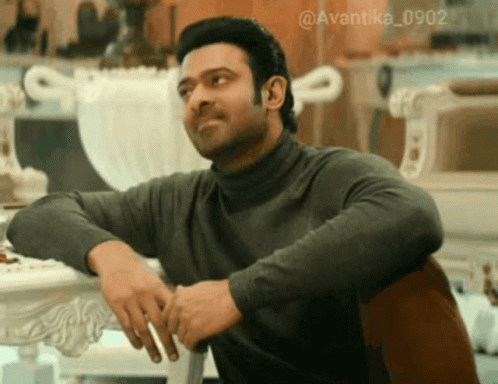 Man In Turtleneck Sitting With Hands On Hips GIF