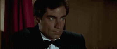 Man In Tuxedo And Bow Tie Sitting In Chair GIF