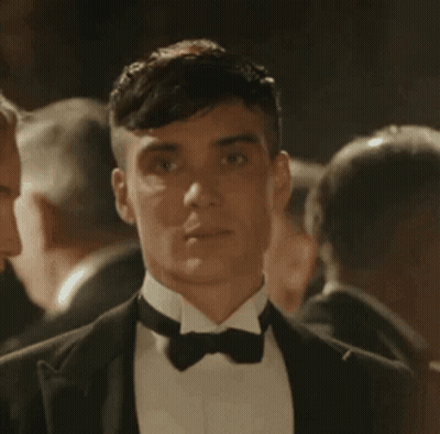 Man In Tuxedo And Bow Tie Standing In Crowd GIF