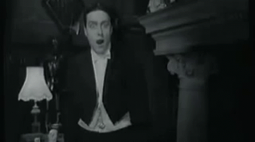 Man In Tuxedo And Bow Tie Standing In Front Of Lamp GIF