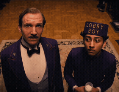 Man In Tuxedo And Man In Lobby Boy Hat GIF