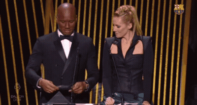 Man In Tuxedo And Woman In Black Dress At Microphones GIF