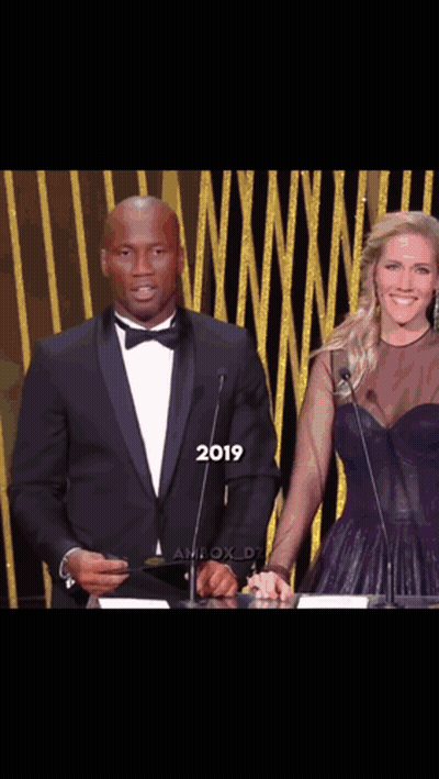 Man In Tuxedo And Woman In Purple Dress At Podium 2019 GIF