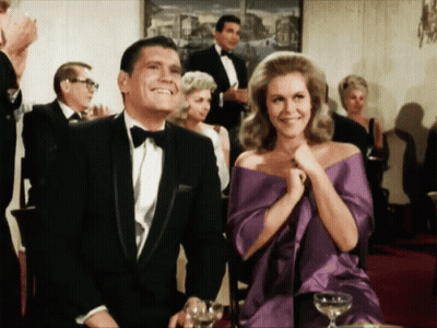 Man In Tuxedo And Woman In Purple Dress Sitting At Table GIF