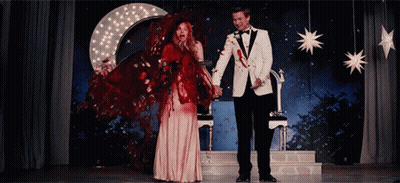 Man In Tuxedo And Woman In Red Dress Holding Hands GIF