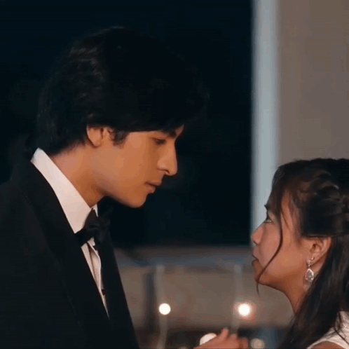Man In Tuxedo And Woman In White Dress Looking At Each Other GIF