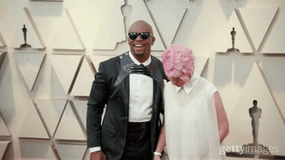 Man In Tuxedo And Woman With Pink Hair Posing GIF