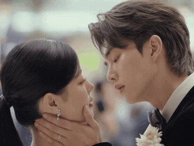 Man In Tuxedo And Woman With Ponytail Kissing GIF