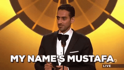 Man In Tuxedo At Microphone Says My Name's Mustafa Live GIF