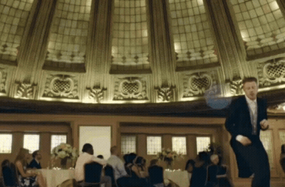 Man In Tuxedo Dancing In Room With People At Tables GIF