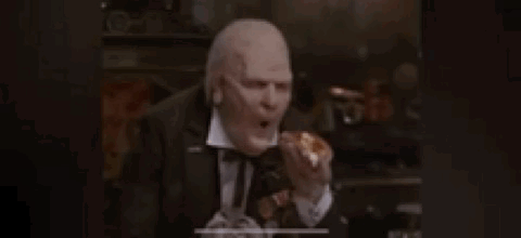 Man In Tuxedo Eating Hamburger In Dark Room GIF