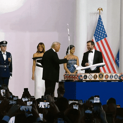 Man In Tuxedo Holding Airplane Before Crowd GIF