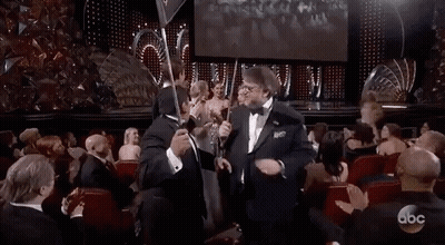 Man In Tuxedo Holding Trophy At Awards Show GIF