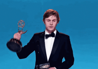 Man In Tuxedo Holding Trophy At Microphone GIF