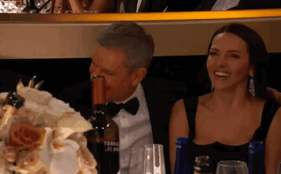 Man In Tuxedo Holding Wine Bottle In Mouth Beside Woman GIF
