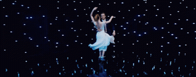 Man In Tuxedo Holding Woman In White Dress On Stage GIF