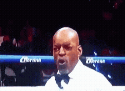 Man In Tuxedo In Boxing Ring With Corona Banner GIF