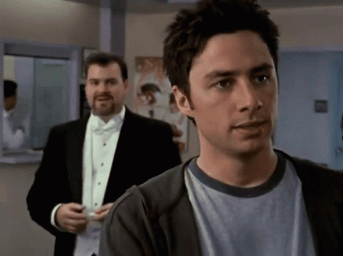 Man In Tuxedo Next To Man In Sweater GIF