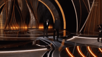Man In Tuxedo On Stage With Cameraman And Live GIF