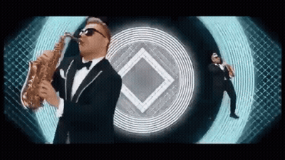 Man in Tuxedo Playing Saxophone With Another Man Behind