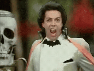 Man In Tuxedo Screaming With Bat On Neck In Front Of Skeleton GIF