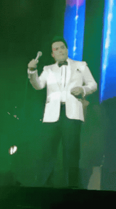 Man In Tuxedo Singing Into Microphone GIF