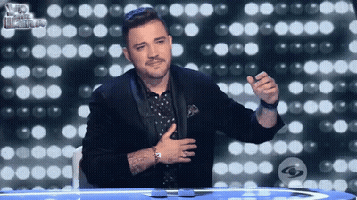Man In Tuxedo Sitting With Hand On Chest GIF