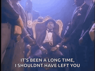 Man In Tuxedo Sitting With Standing Men GIF