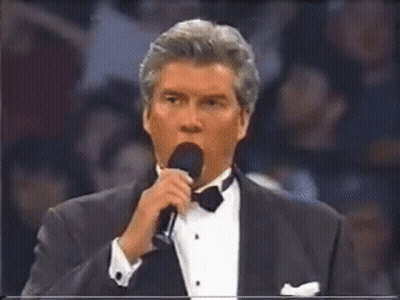 Man In Tuxedo Speaking Into Microphone GIF