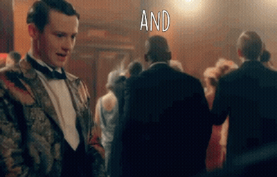 Man In Tuxedo Standing Before Crowd With Word And GIF