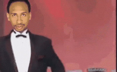 Man In Tuxedo Standing Before Red Background GIF