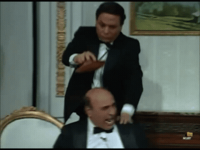 Man In Tuxedo Standing Next To Another Man GIF