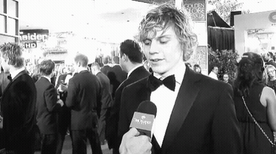 Man In Tuxedo Talking Into Microphone In Front Of Crowd GIF